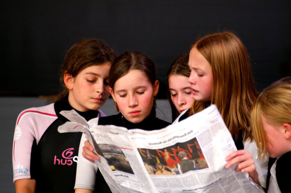 5 Mädchen schauen gemeinsam in eine Zeitung